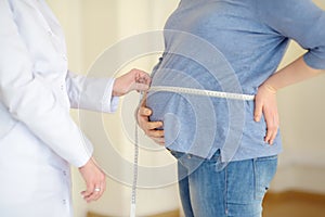 Gynecologist doctor measures with centimeter tape of a pregnant woman. Medical insurance childbearing. Family doctor for gestation