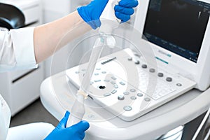 Gynecologist doctor prepares an ultrasound machine for the diagnosis of the patient. Applies gel to a transvaginal ultrasound