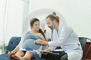 Gynecologist doctor with stethoscope listening and examining to pregnant woman baby heartbeat in medical office at at hospital