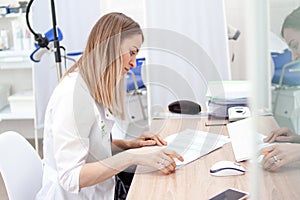 Gynecologist doctor in white uniform in clinic hospital works on computer. Gynecological cabinet with chair and other