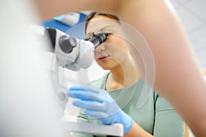 Gynecologist examines a patient using microscope in a gynecological chair. Doctor performs a colposcopy on a young girl in a photo