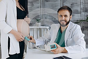 A gynecologist examines a pregnant woman. Fetal doppler heart auscultation