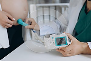 A gynecologist examines a pregnant woman. Fetal doppler heart auscultation