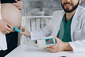 A gynecologist examines a pregnant woman. Fetal doppler heart auscultation