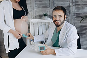 A gynecologist examines a pregnant woman. Fetal doppler heart auscultation