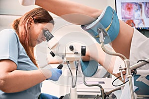 Gynecologist examining female patient with colposcope. photo