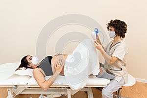 Gynecologist holding a pelvic floor muscle exercise device to prepare for the giving of birth of a woman lying photo