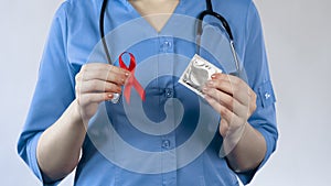 Gynecologist holding red ribbon and condom, AIDS awareness, warning about STI photo