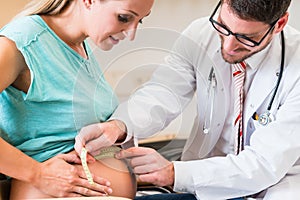 Gynecologist measuring belly of pregnant woman