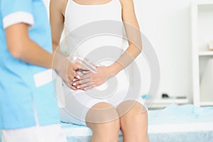 Gynecologist with medical instrument with mirror standing in front of woman with adnexitis