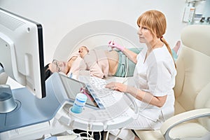 Gynecologist performing extra fetal ultrasound to adult pregnant woman