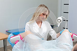 A gynecologist performs a colposcopy on a young girl in a gynecological chair in a modern medical office. Prevention and