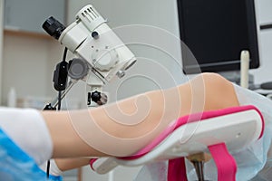 A gynecologist performs a colposcopy on a young girl in a gynecological chair in a modern medical office. Prevention and photo