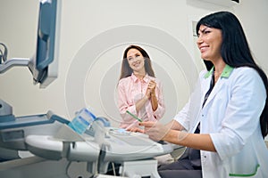 Gynecologist and pregnant woman watching ultrasound results on monitor in clinic