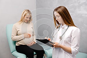 Gynecologist talking with a young female patient during a medical consultation in the gynecological office and and making entries