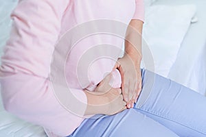 Gynecology concept. Hands of young woman on stomach as suffer from menstruation cramp, indigestion, gastrointestinal, diarrheas or