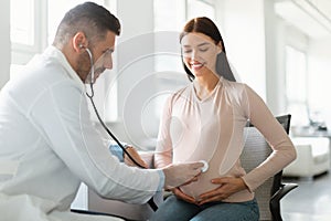 Gynecology consultation. Happy young pregnant woman visiting gynaecologist in maternity clinic, doing medical check-up photo