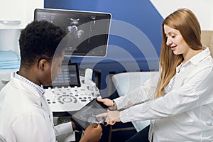 Gynecology consultation, ultrasound concept. Smiling African man doctor obstetrician showing digital tablet with