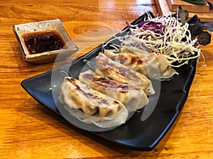 Gyoza dumplings in beautiful black dish and soy sauce on the wooden table