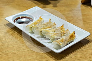 Gyoza and sauce on a white plate.