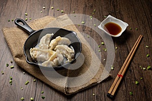 Gyozas, fried japanese dumplings on cast-iron pan served with soy sauce.