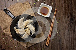 Gyozas, fried japanese dumplings on cast-iron pan served with soy sauce. photo