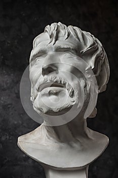 Gypsum copy of ancient statue Seneca head on dark textured background. Plaster sculpture man face.