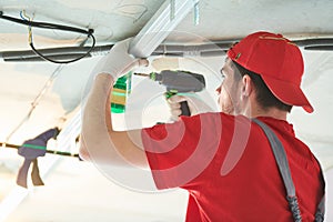 Gypsum plasterboard work. Drywall construction at home. Contractor worker installing metal frame on ceiling