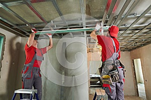 Gypsum plasterboard work. Drywall construction at home. Contractor worker installing metal frame on ceiling