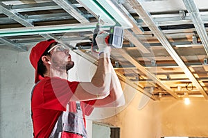 Gypsum plasterboard work. Drywall construction at home. Contractor worker installing metal frame on ceiling