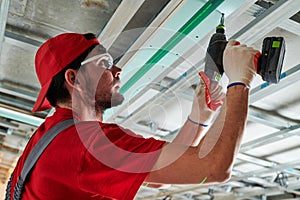 Gypsum plasterboard work. Drywall construction at home. Contractor worker installing metal frame on ceiling