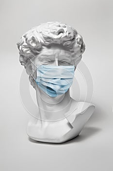 Gypsum statue of David's head. Man. Creative. Plaster statue of David's head in medical mask.