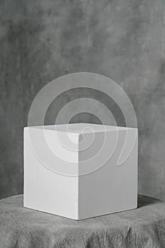 Gypsum white cube, simple geometric shape on a gray fabric art background for learning to draw.