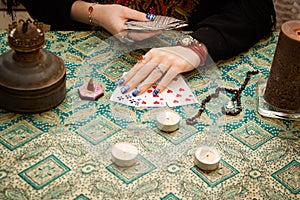 Gypsy fortune girl stands near the table with magical attributes: candles, cards, bahurs and etc