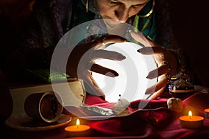 Gypsy fortune teller woman with her hands above crystal ball photo