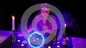 A gypsy at the table is engaged in magic with a crystal ball that emits electric sparks and bubbles