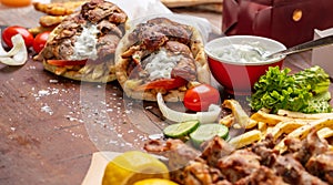 Gyro pita, shawarma, souvlaki. Two pita bread wraps and meat skewers on wooden table