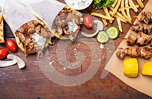Gyro pita, shawarma, souvlaki. Two pita bread wraps and meat skewers on wooden table