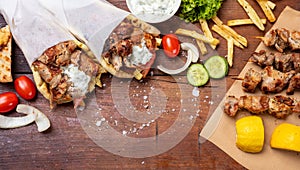 Gyro pita, shawarma, souvlaki. Two pita bread wraps and meat skewers on wooden table