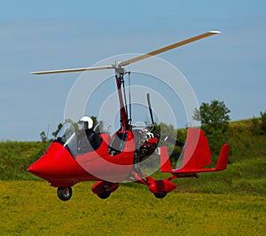 Gyroplane landing over green field photo