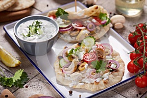Gyros flatbread filled with chicken meat, tzatziki sauce and vegetables. photo