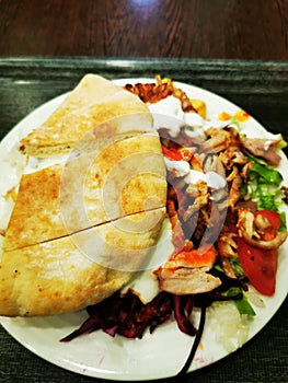 Gyros pita with meat and vegetables on a wooden table in a restaurant