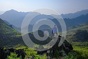 Ha Giang / Vietnam - 01/11/2017: Backpacker standing on outcrop overlooking karst mountain scenery in the North Vietnamese region