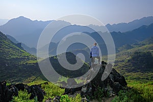 Ha Giang / Vietnam - 01/11/2017: Backpacker standing on outcrop overlooking karst mountain scenery in the North Vietnamese region photo