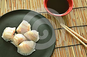 Ha Kao or white dumpling stuffed shrimp and pork on plate dipping soy sauce