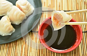 Ha Kao or white dumpling stuffed shrimp and pork on plate dipping soy sauce