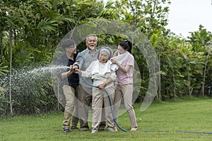 Haapy Asian family with smil lovely are watering a tree by tube in garden at outdoor house in morning