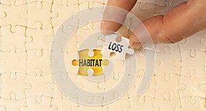 Habitat loss symbol. Concept words Habitat loss on white paper puzzles. Beautiful yellow table yellow background. Businessman hand
