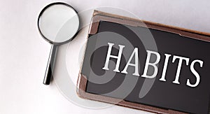 HABITS - word in electronic notebook on white background with magnifying glass