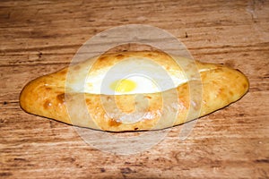 Hachapuri on Adjara open pie with egg on wooden background